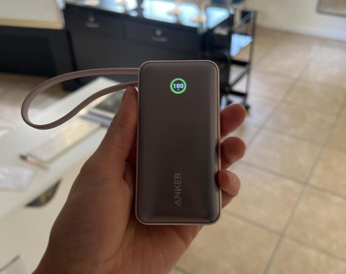 A hand holding a fully charged Anker portable power bank, a great Prime Day electronics deal for your tech.