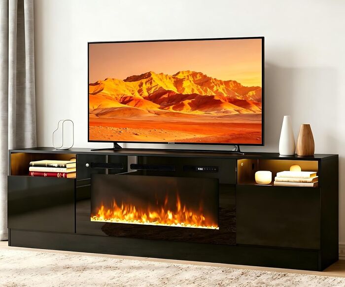 A large flat-screen TV displaying a mountain landscape, placed on a black media console with a fireplace, a Prime Day electronics deal.