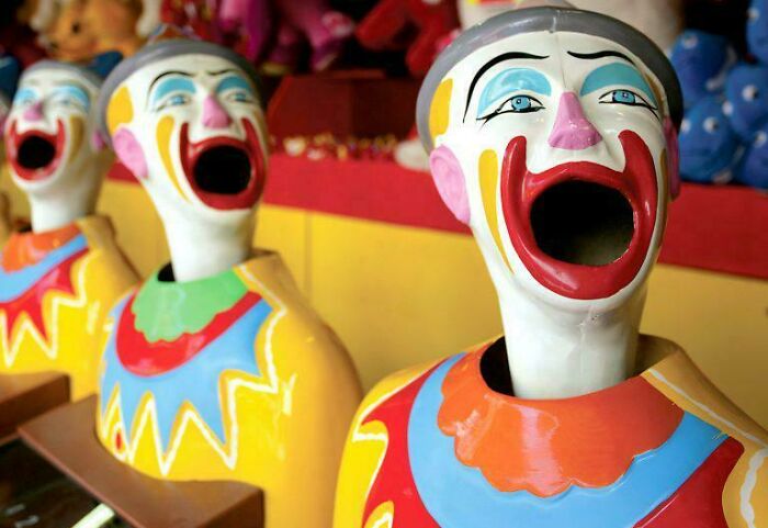 Creepy design fail: three carnival clown figures with wide open mouths, appearing uncomfortable.