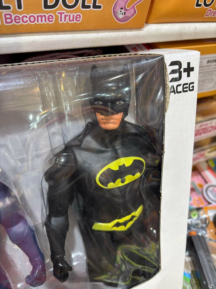 A Batman action figure in a box with a disfigured face, a creepy design fail.
