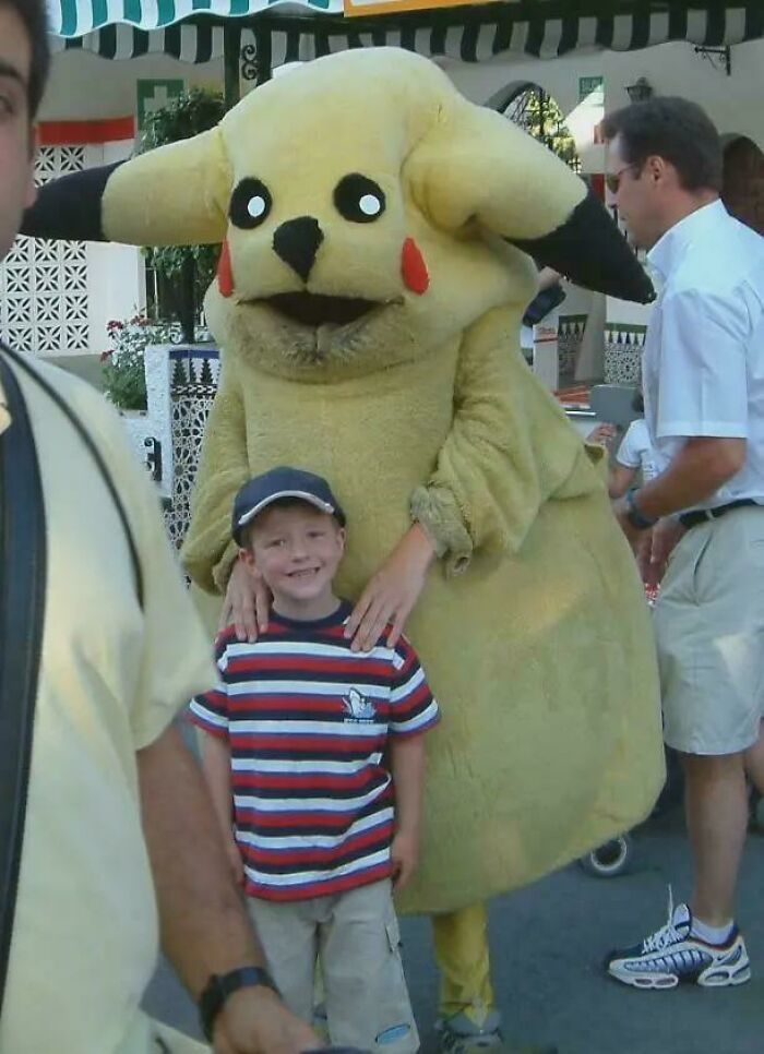 A small boy smiling next to a person in a poorly designed Pikachu costume, a creepy design fail.