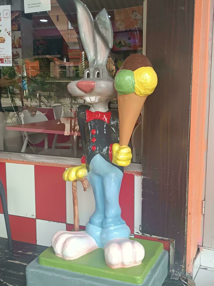 A large, unsettling Bugs Bunny-like statue holding an ice cream cone outside a shop, a creepy design fail.