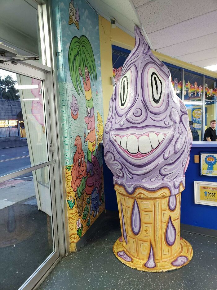 A creepy, purple, melting ice cream cone mascot with a wide, unsettling grin, a design fail.