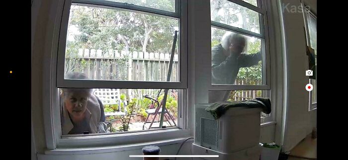 Two older individuals peering through a window into a home, depicting an invasion of privacy by horrible landlords.
