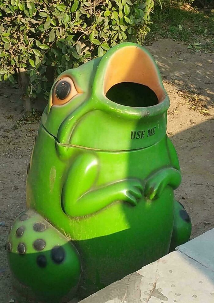 A green frog-shaped trash can with an open mouth, a design fail that makes people feel uncomfortable.