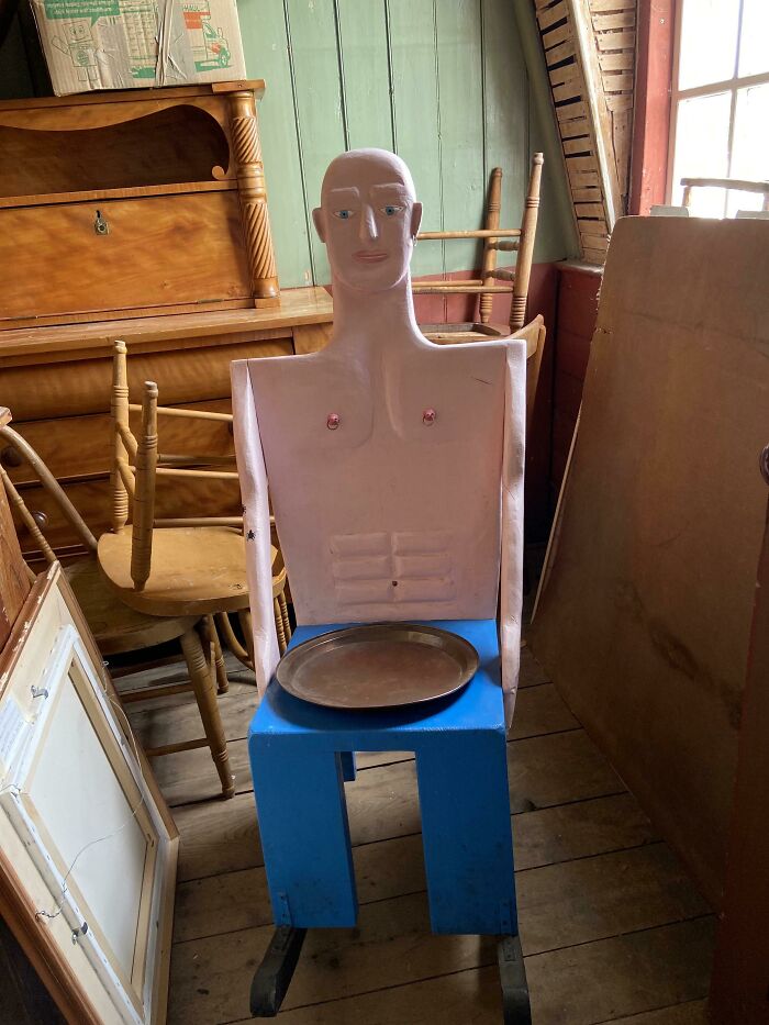 A pink mannequin-like figure with a blue base, a creepy design fail sitting in a cluttered room.