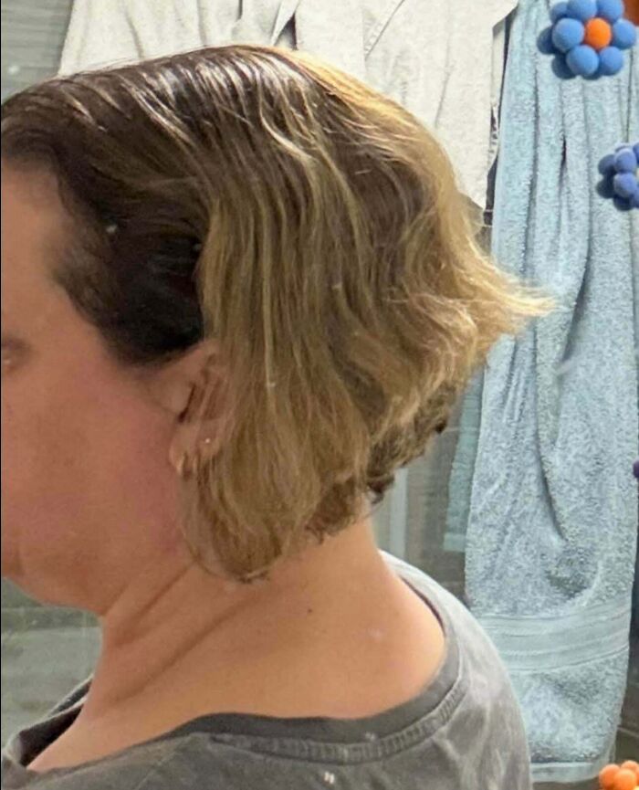 A woman with short, wavy, light brown hair looking at hair salon disasters, showing a bad haircut from the side.
