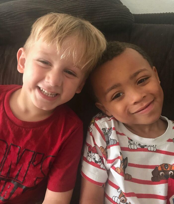 Two young boys, one with blonde hair in a red shirt and one with dark hair in a striped shirt, smiling together, embodying adoption stories.
