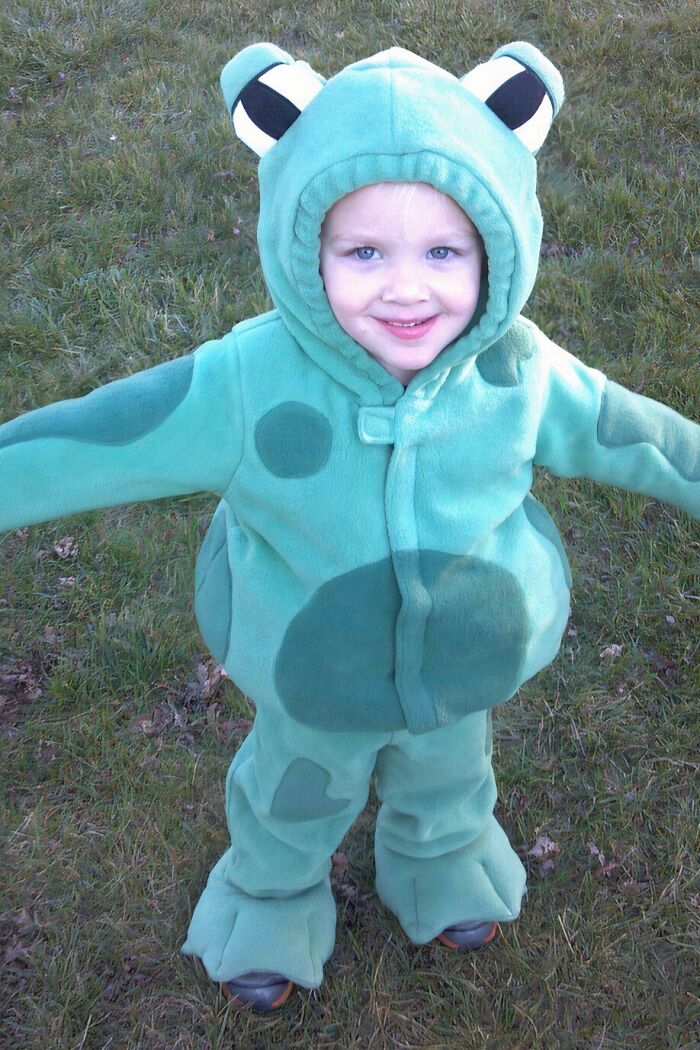 A young child in a frog costume, representing a happy part of adoption stories.