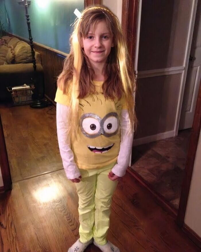 A young girl with long hair, smiling in a yellow Minion shirt and lime green pants, showcasing her adoption story.
