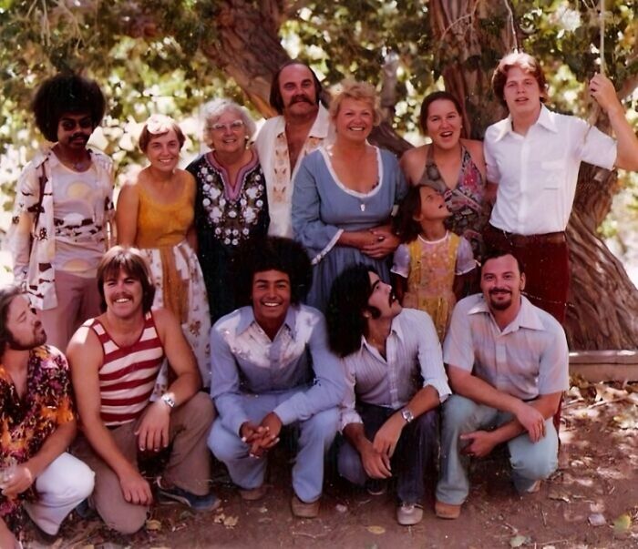 A vintage photo of a large, diverse family gathered outdoors, showcasing various adoption stories and happy families.