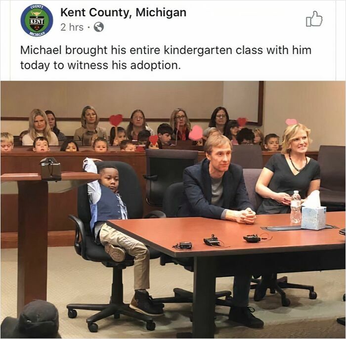 A young boy at an adoption hearing with his kindergarten class in the background, a heartwarming part of adoption stories.