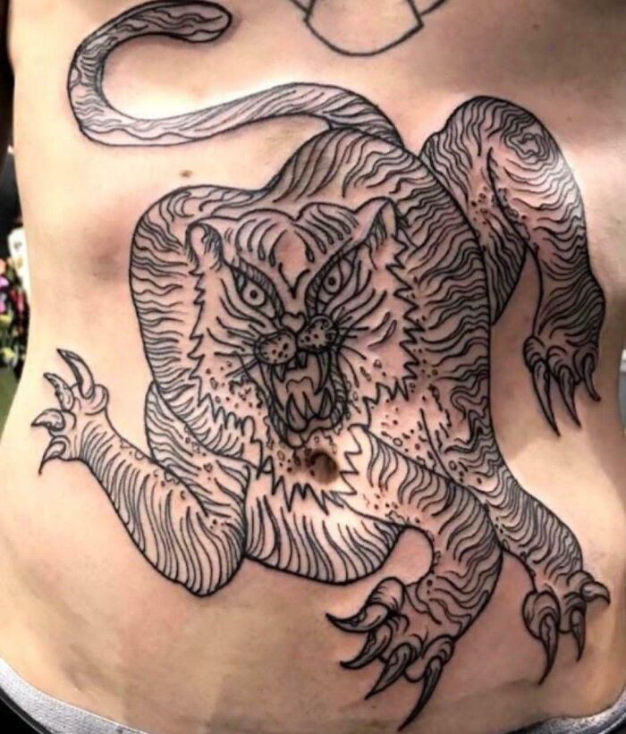 Tattoo fail of fierce tiger with distorted anatomy on torso