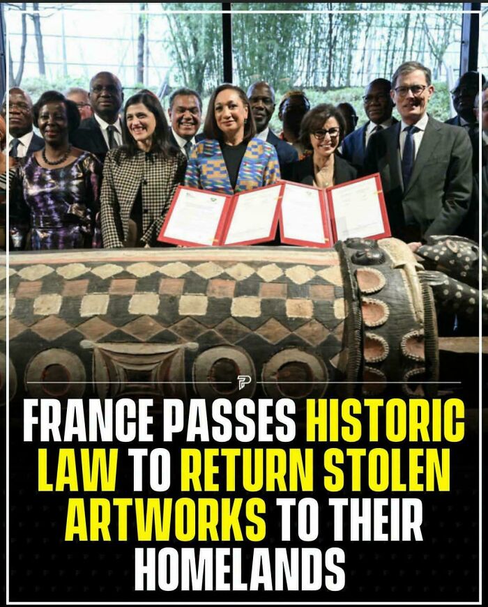 A group of people standing behind a table with documents, a historic law to return stolen artworks.