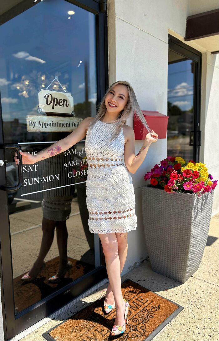 A smiling woman in an incredible white crochet dress with cutouts, shared by crochet enthusiasts.
