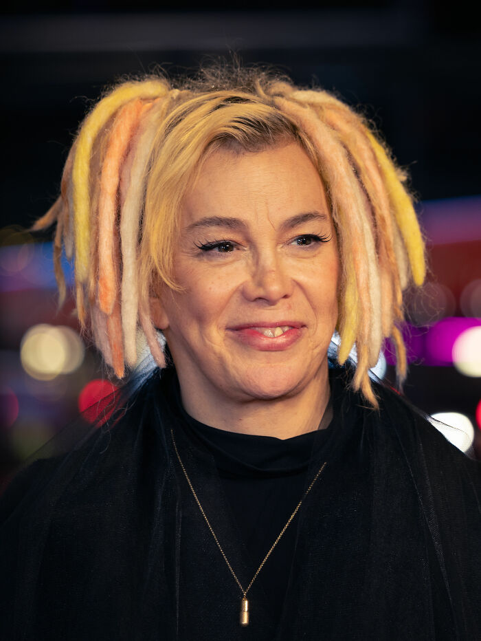 Close-up of Lana Wachowski with colorful dreadlocks, smiling slightly, showcasing her unique style and career highlights.