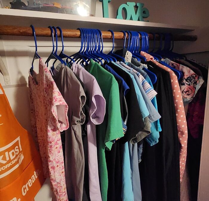A closet rod filled with clothes on blue hangers, representing practical home finds on sale for Prime Day.