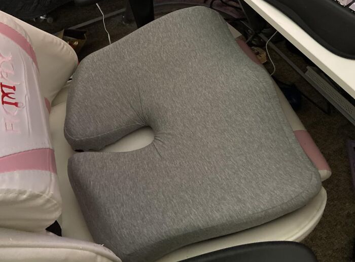 A gray ergonomic seat cushion, a comfortable home find on Prime Day, rests on a white chair.