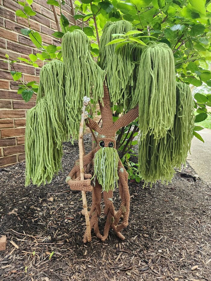 An incredible crochet tree with green yarn for leaves, big eyes, and holding a staff, shared by enthusiasts.
