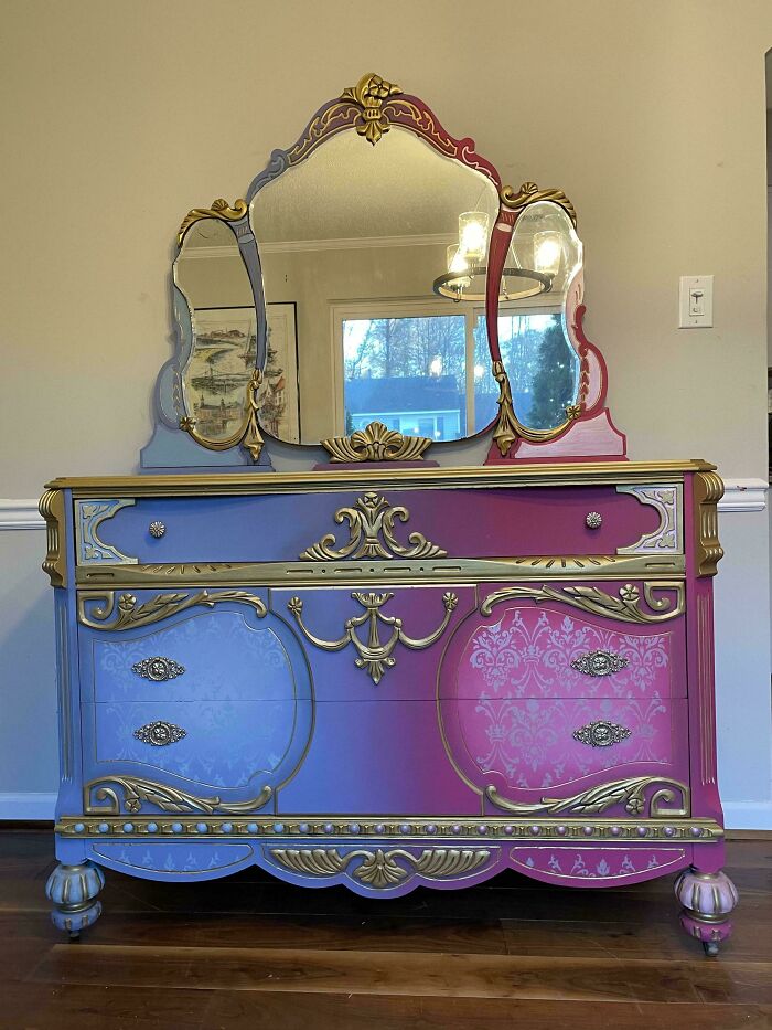 A revived old piece of furniture, a vanity dresser with a mirror, painted in purple, pink, and gold.