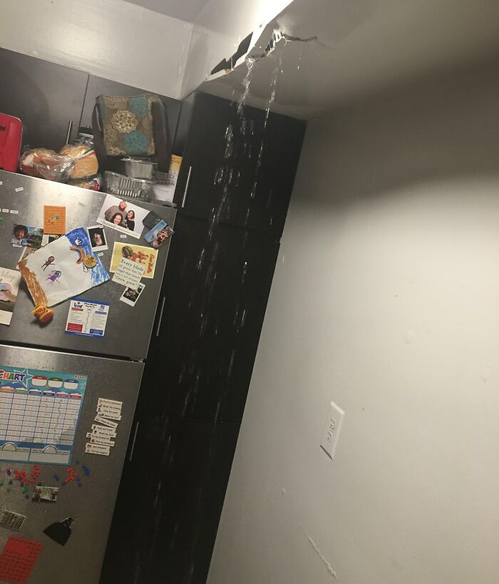 Water leaking from a damaged ceiling onto a kitchen counter and refrigerator, a disastrous result of horrible roommates.