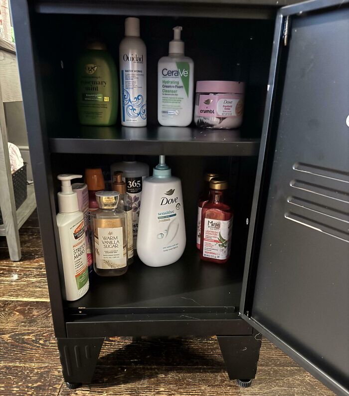 An open cabinet filled with numerous bottles of shampoo, lotion, and body wash, indicating a horrible roommate's hoarding.