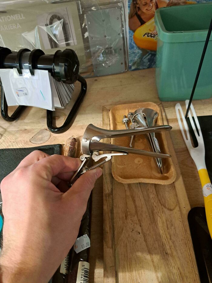 A hand holds a metal medical speculum, a thing that should be left alone.