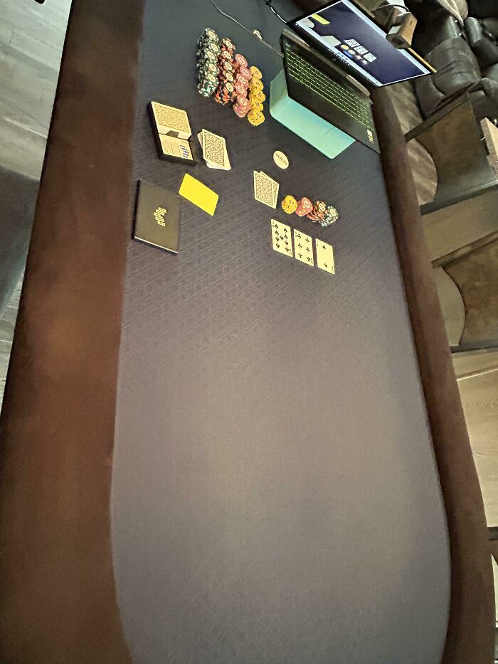 An overhead view of a poker table with cards, chips, and a laptop, showing wholesome things.