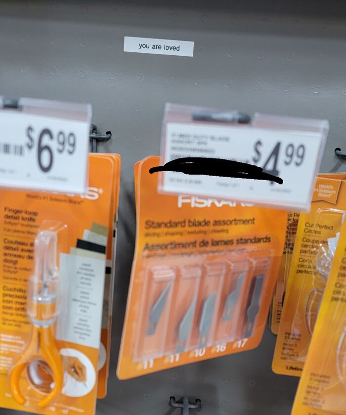 An unusual but wholesome sight of a sticky note saying 'you are loved' on a store shelf among sharp blades.