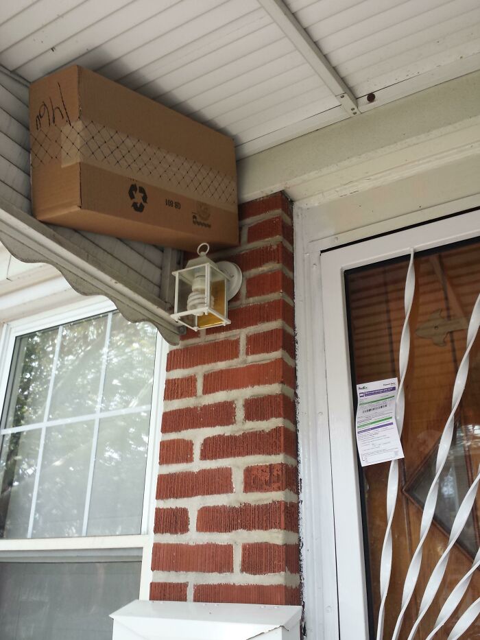 A package precariously balanced on a porch overhang, showing an unusual delivery fail.