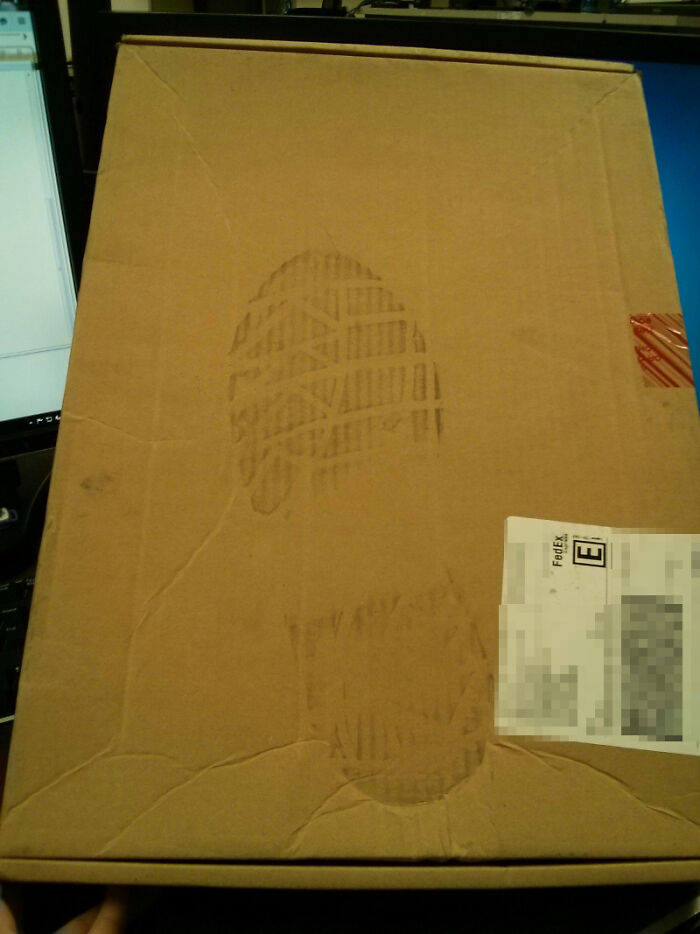 A brown delivery box with a clear footprint on top, highlighting a delivery fail.