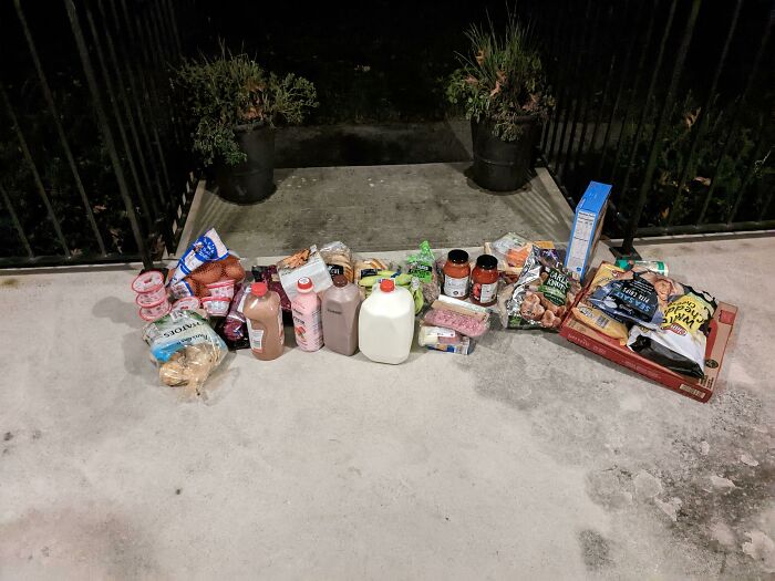 Groceries spread out on a concrete porch, indicating a possible delivery fail or unusual drop-off.