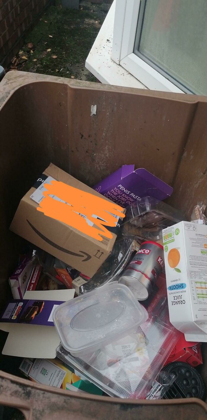 An Amazon package inside a brown bin with other trash, highlighting a typical delivery fail for online orders.