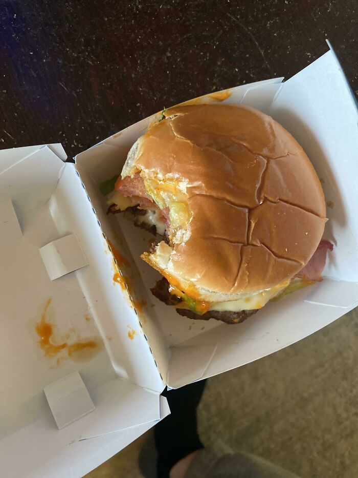 A half-eaten hamburger in its box, illustrating a hilarious or frustrating delivery fail experience.