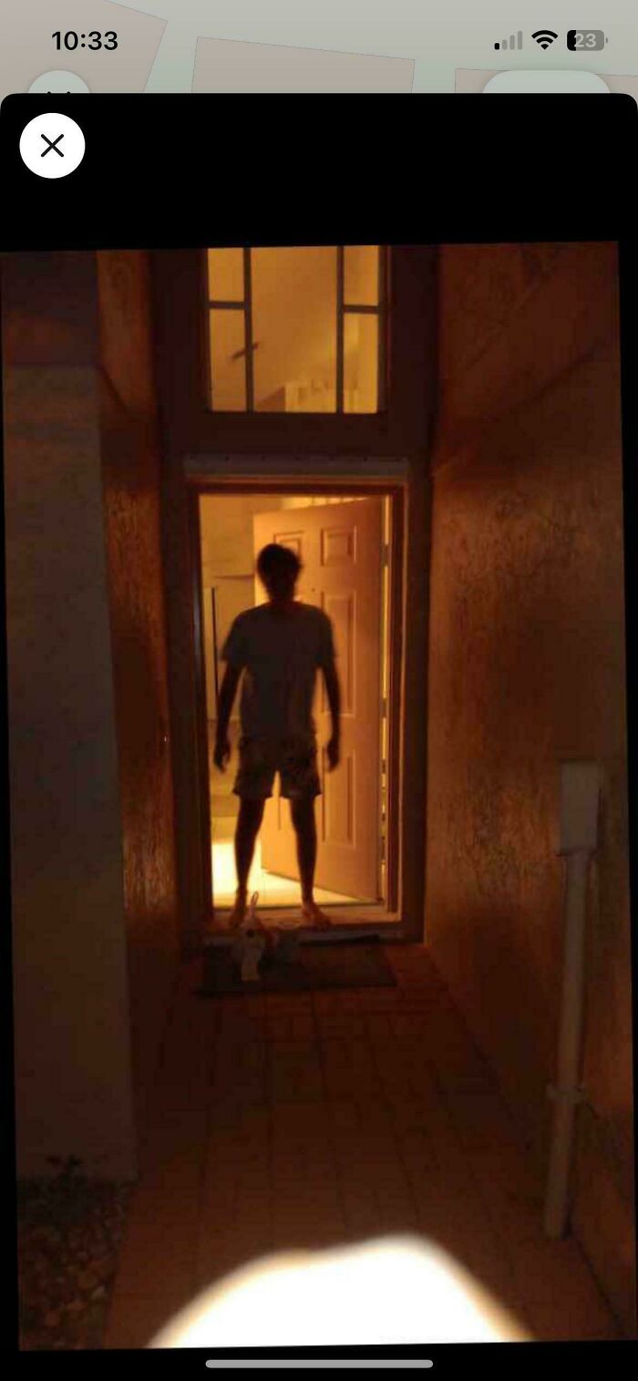 A dark, eerie silhouette of a person stands in a brightly lit doorway at night, showcasing a creepy delivery fail.