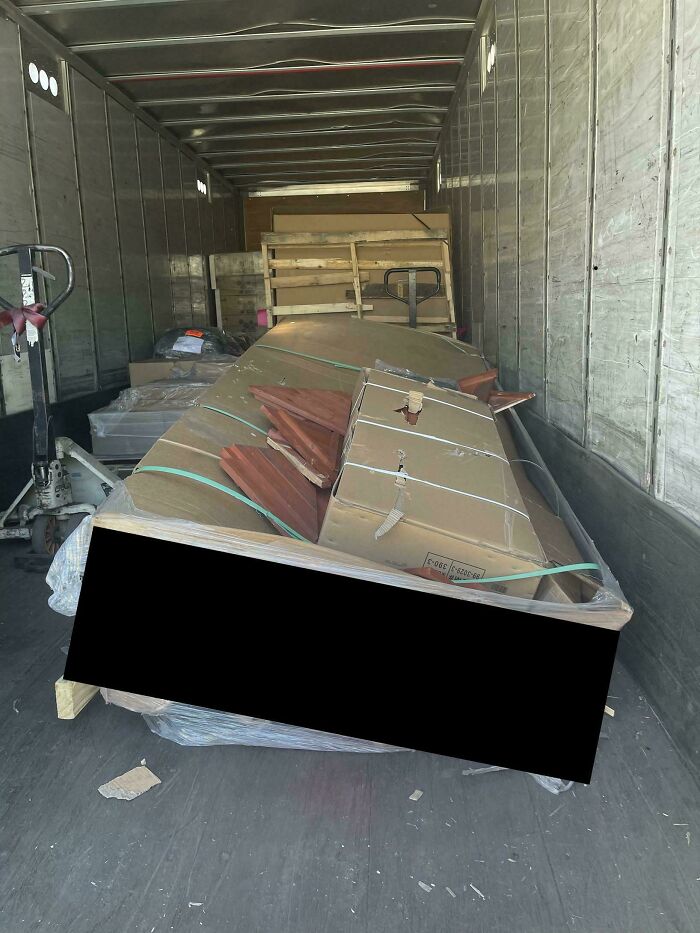 A chaotic stack of packages, some damaged, inside a delivery truck, illustrating a delivery fail.