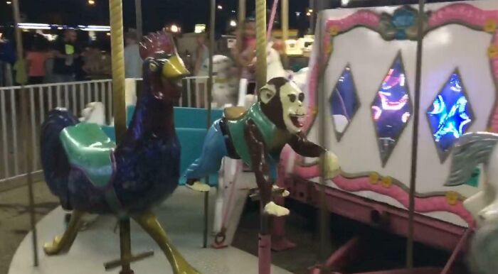 Creepy design fail carousel with a chicken and a monkey ride, featuring unsettling expressions and outdated appearance.