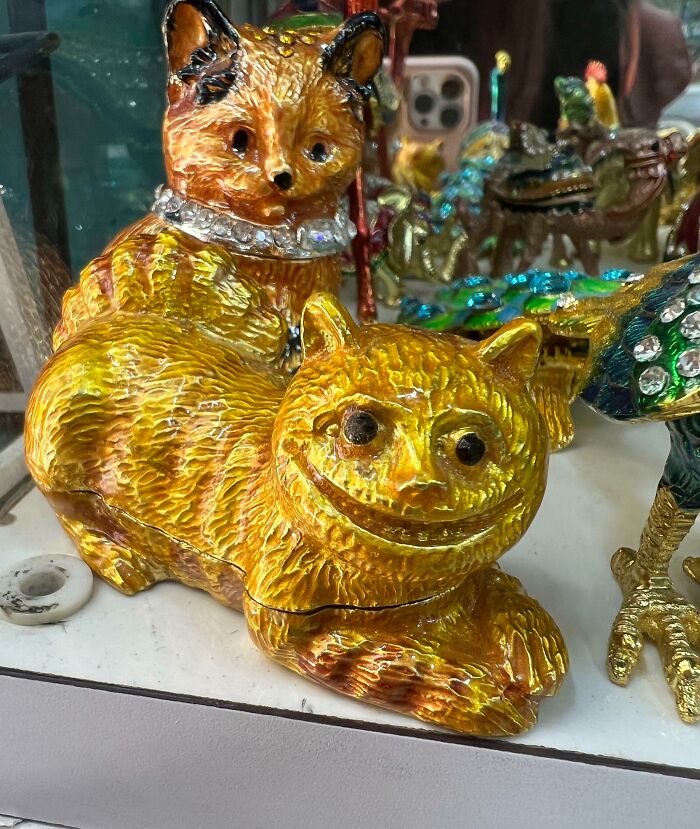Two creepy, golden cat figurines with exaggerated grins and rhinestone collars, a design fail.