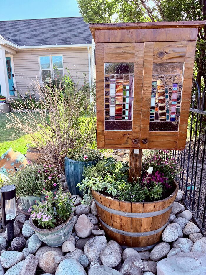 A beautifully crafted wooden handmade project, a small cabinet with stained glass, surrounded by flowers.
