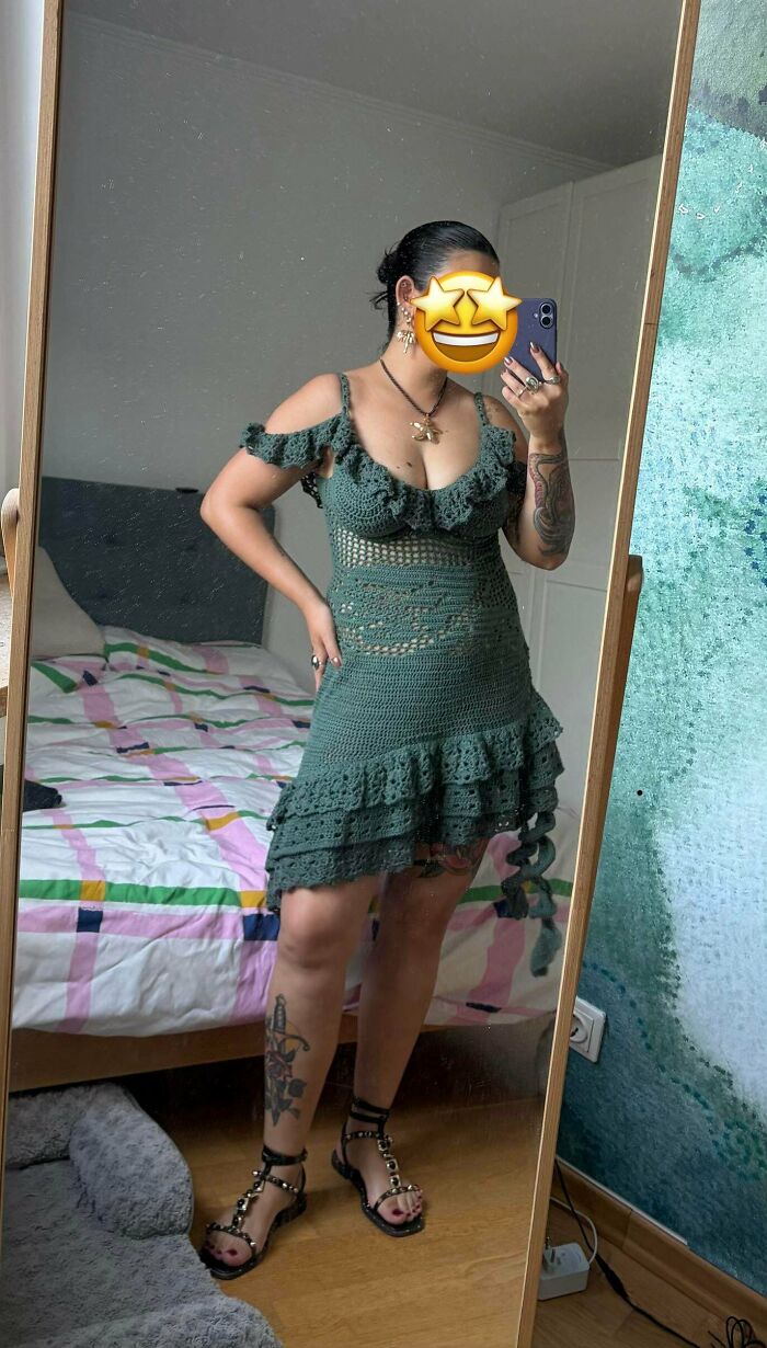 A crochet enthusiast models an incredible, stylish green crochet dress with ruffled details and intricate patterns.
