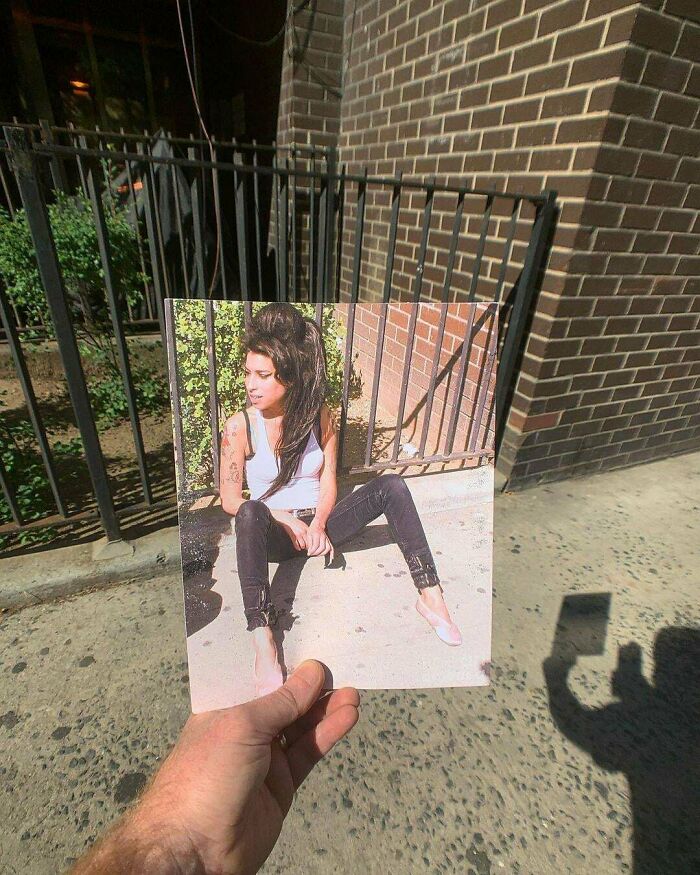 A hand holds a picture of Amy Winehouse sitting on a curb in front of a brick wall, showing how much America has changed.