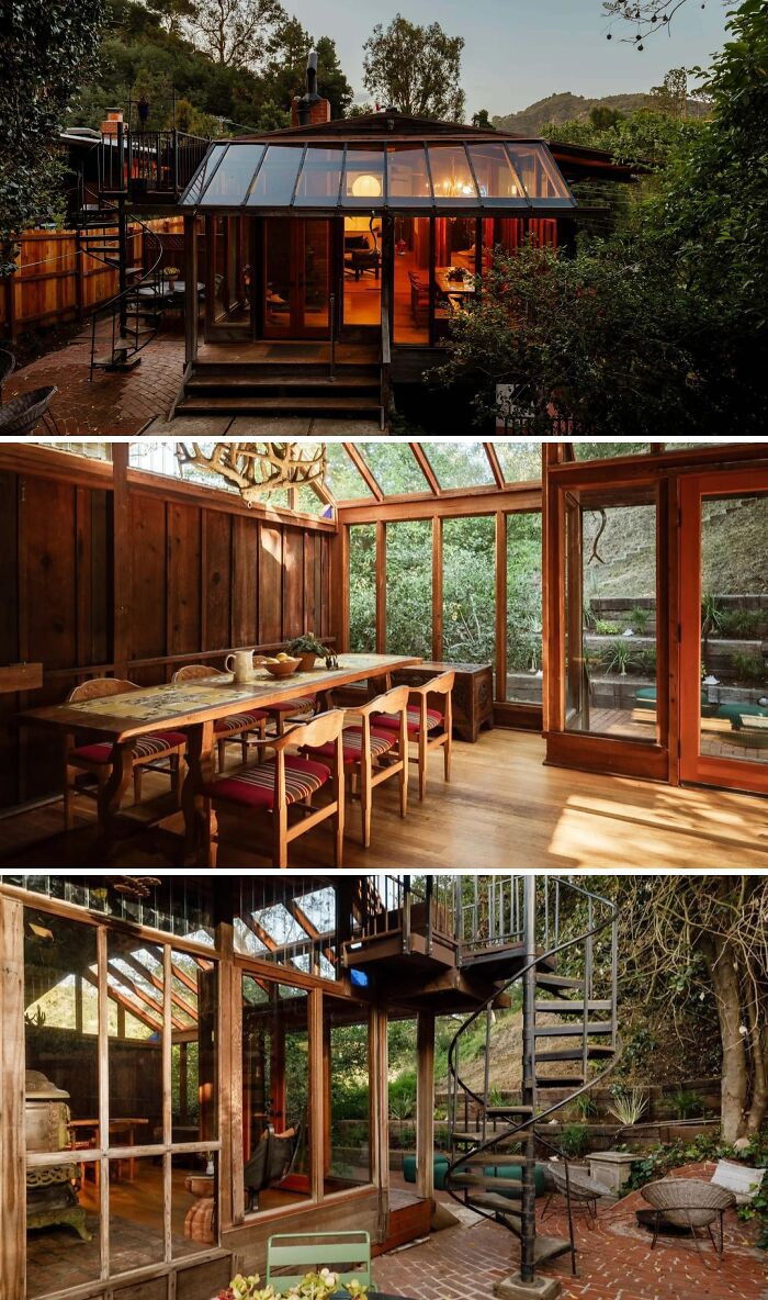 A beautiful glass-enclosed dining room in a cool, wacky, and unusual home surrounded by trees with a spiral staircase.