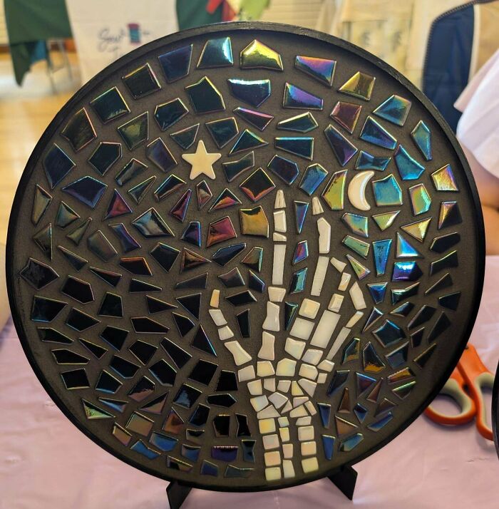 A round mosaic handmade project featuring a skeleton hand, moon, and star, crafted with patience.