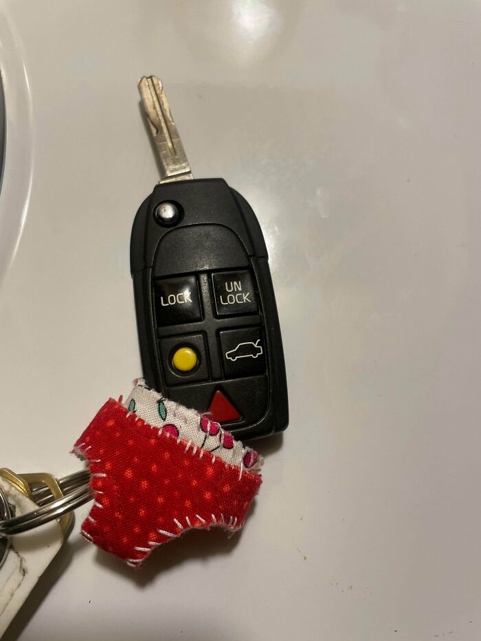 A car key with a small, red, patterned fabric charm attached, a clever solution for personalization.