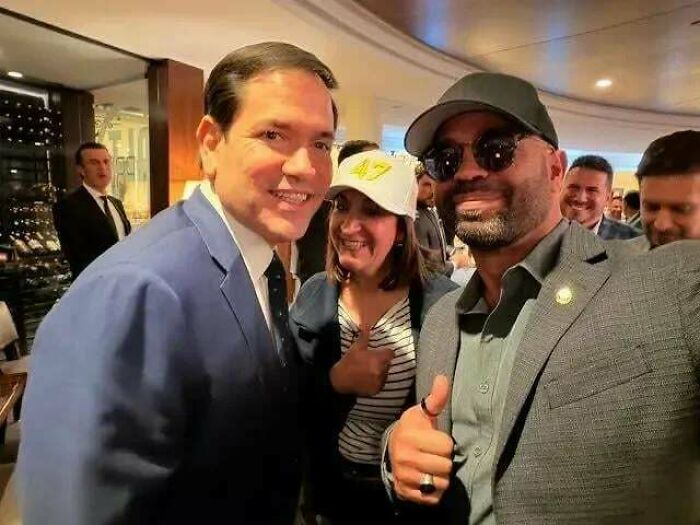 Two men smiling and posing for a photo at an event, with one giving a thumbs up, showing real-life chaotic good posts.
