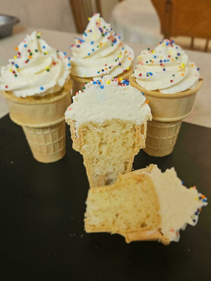 Vanilla cupcakes in ice cream cones with sprinkles, one cut to show the inside, a delicious treat.