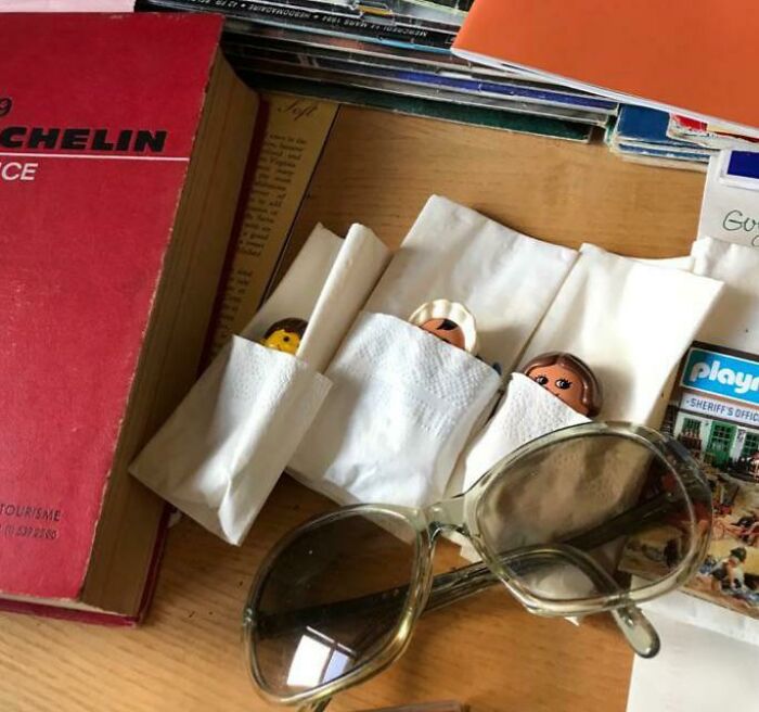 Image of miscellaneous items on a table, including a red Michelin guide, sunglasses, and small toy figures wrapped in tissue. These items might be part of an inspiring home renovation.
