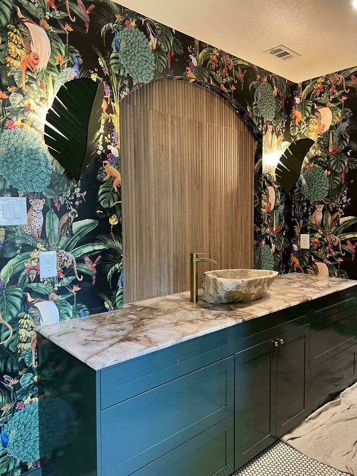 Home renovation showing a bathroom with unique jungle-themed wallpaper and a stone sink.