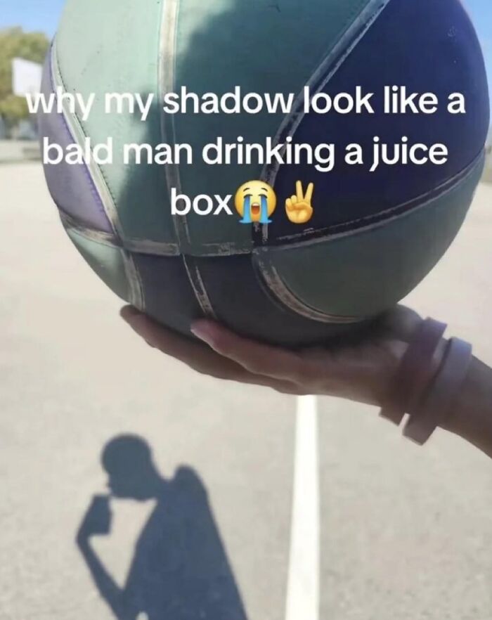 A person holding a basketball with a shadow that resembles a bald man drinking a juice box, a funny image from savage comments.