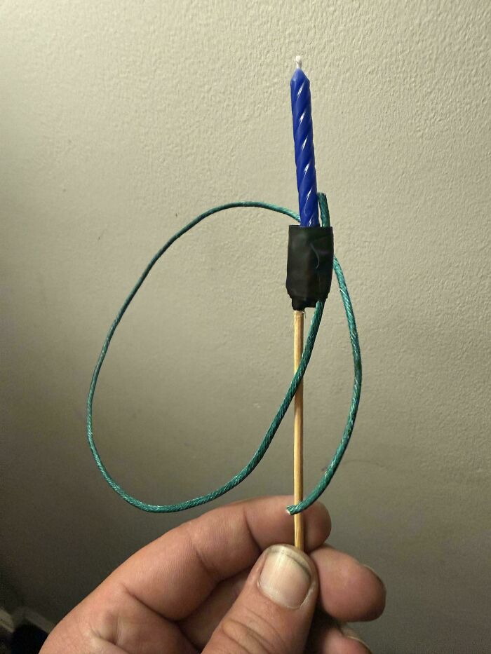 A blue birthday candle taped to a wooden skewer with a green string, a clever solution for random junk.